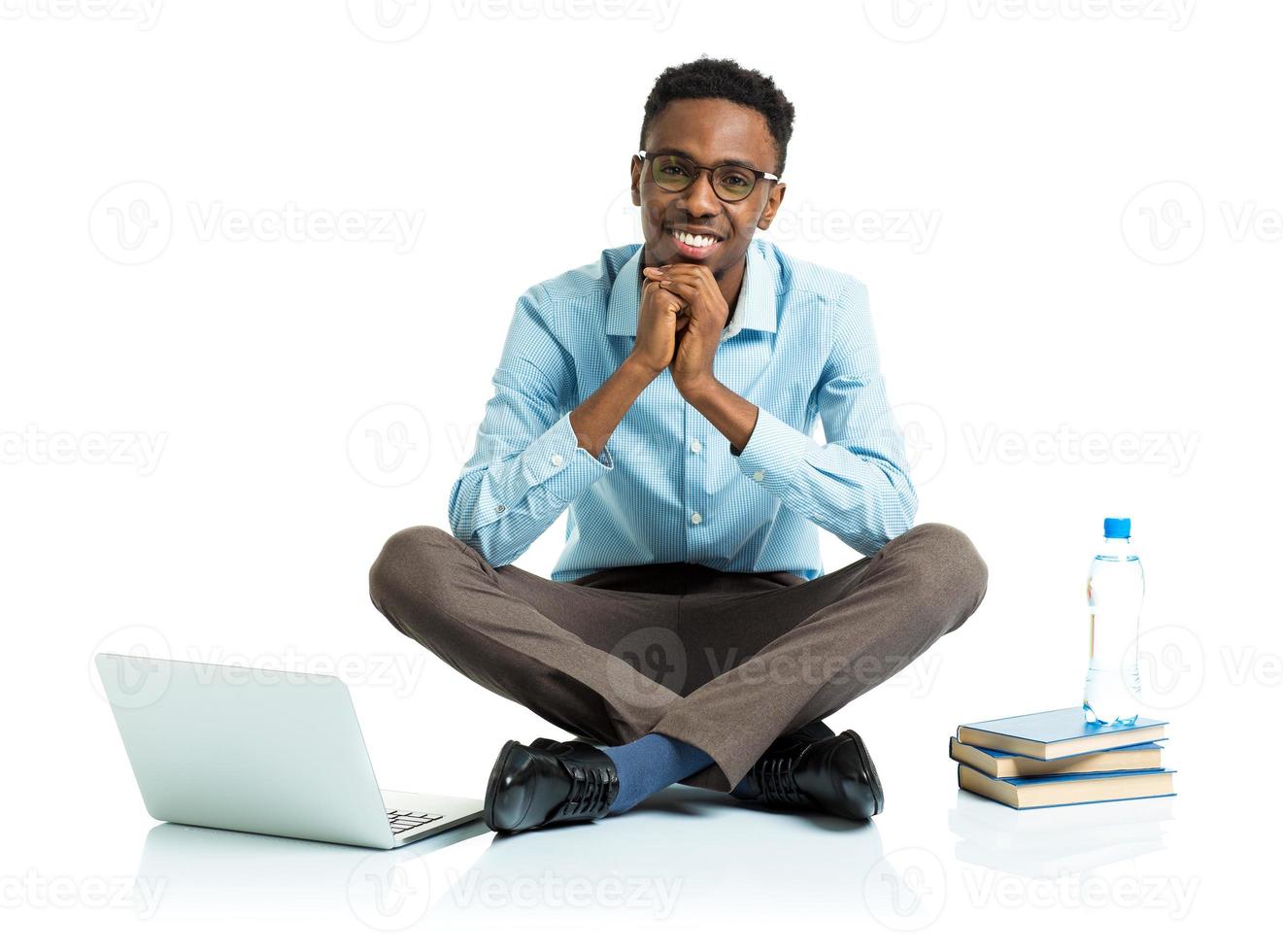 Happy african american college student sitting on white with laptop and some books photo