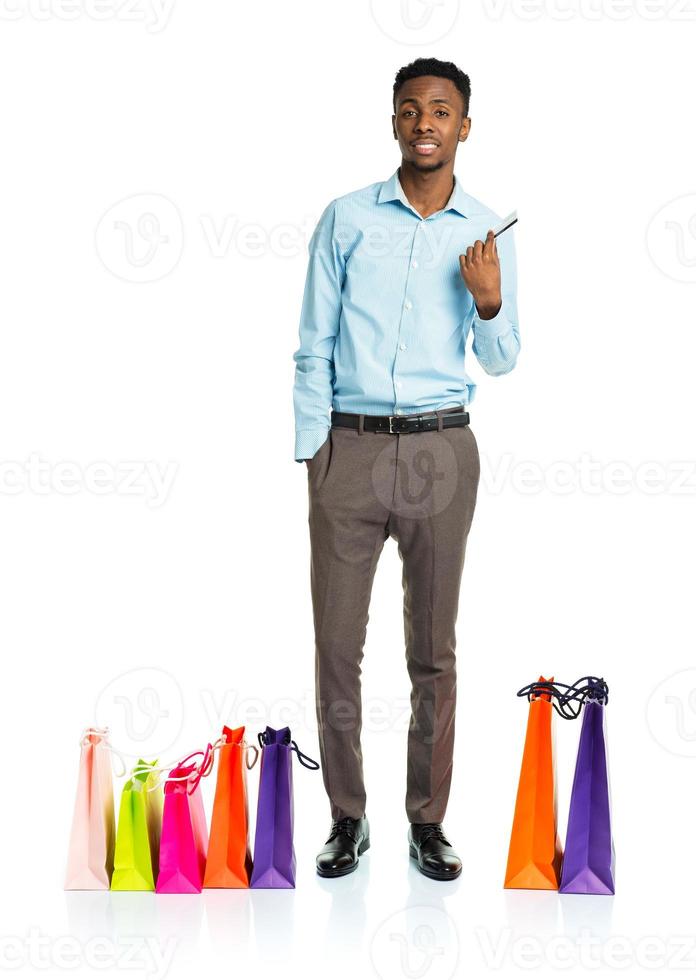 Happy african american man with shopping bags and holding credit card on white background photo