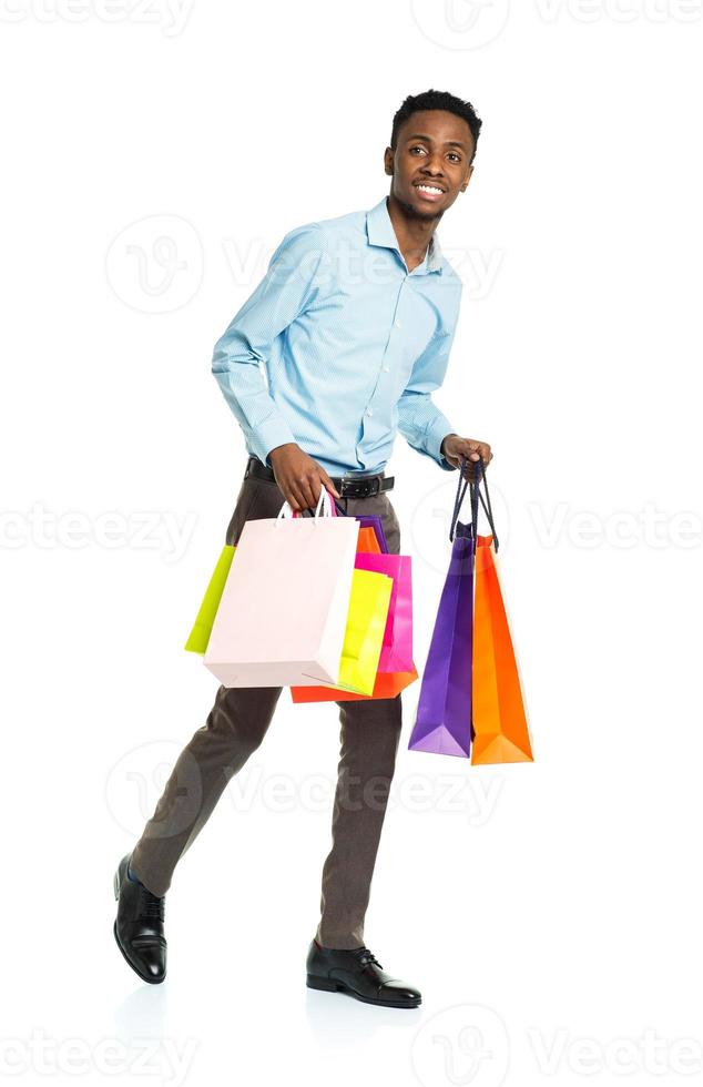 Happy african american man holding shopping bags on white background photo