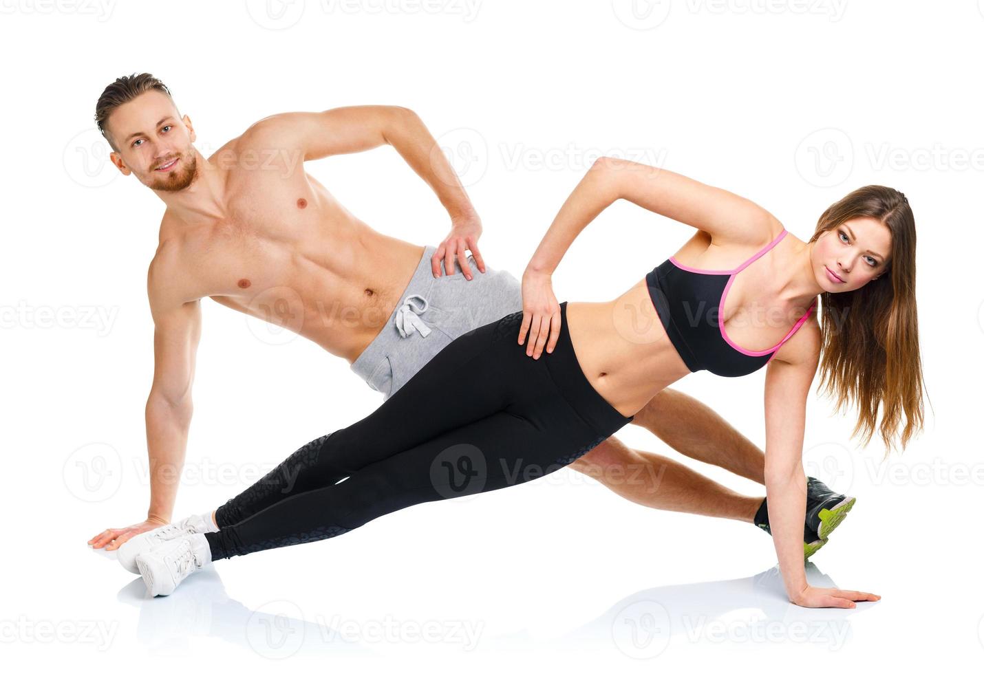 Athletic attractive couple - man and woman doing fitness exercises on the white photo