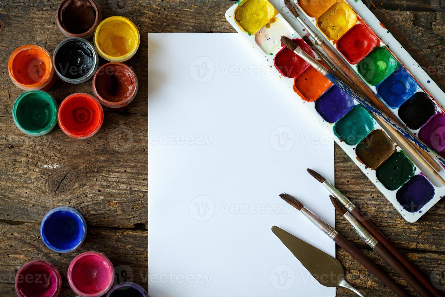 Painting set. Paper, brushes, paints, watercolor, acrylic paint on a wooden background top down view photo