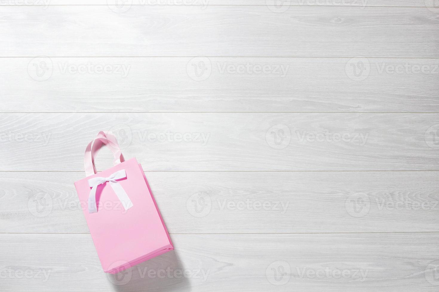 enamorado rosado papel Bolsa de regalo en blanco de madera antecedentes. parte superior vista, Copiar espacio San Valentín concepto. cumpleaños regalo bolsa. romántico amor fiesta regalo accesorios. Bosquejo modelo blanco escritorio foto