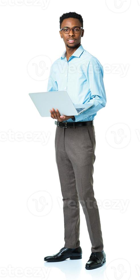 Happy african american college student standing with laptop on white photo