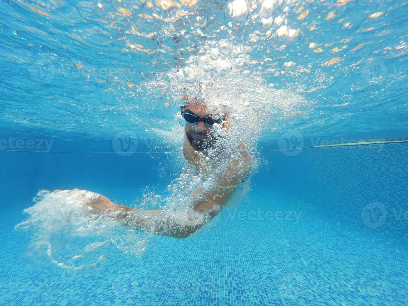 Beard man with glasses swimming under water in the pool photo