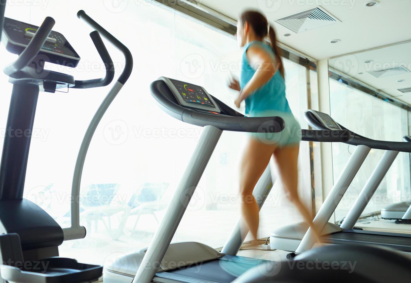 Woman running on treadmill in gym photo