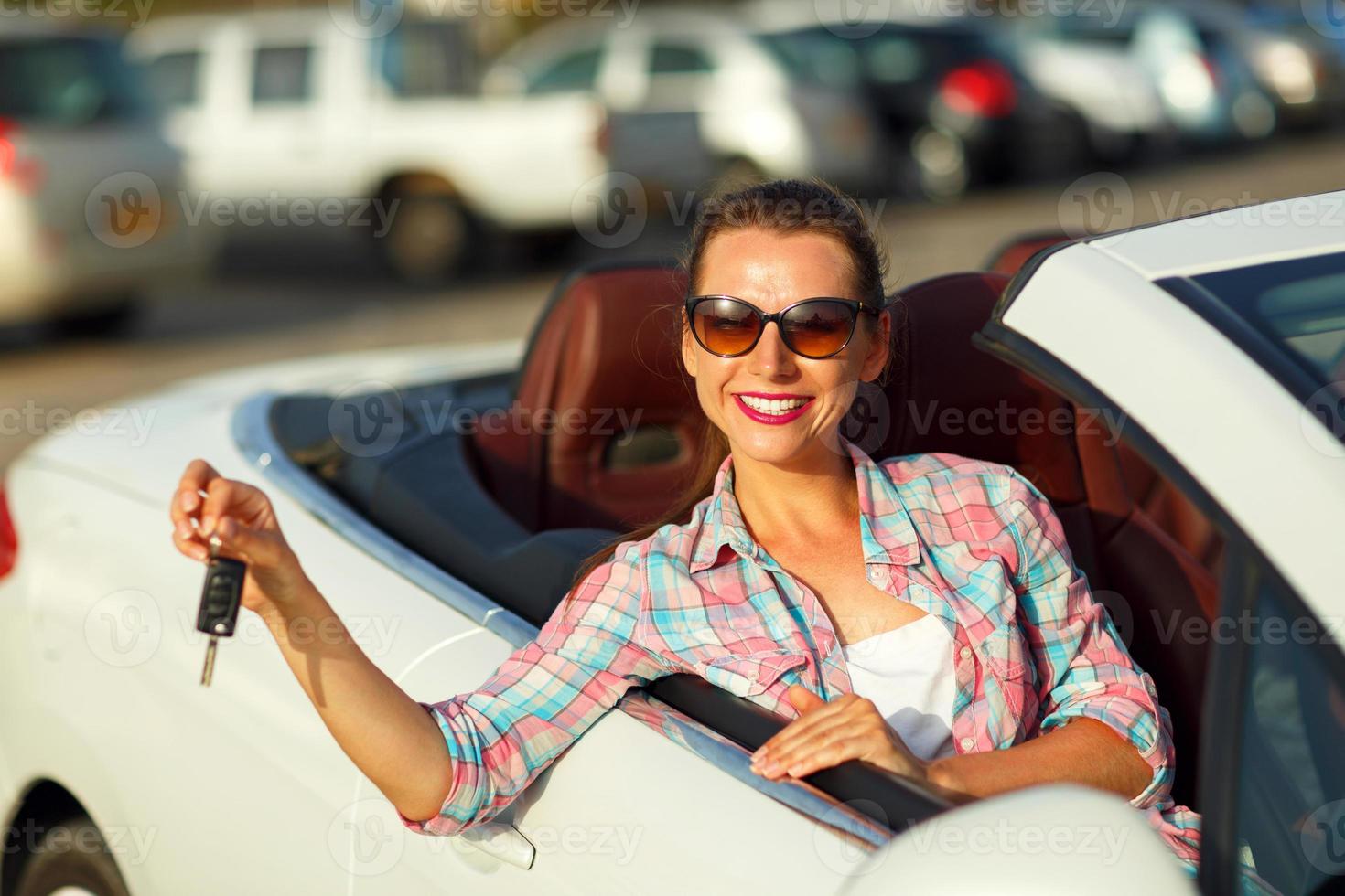 Young pretty woman sitting in a convertible car with the keys in hand photo