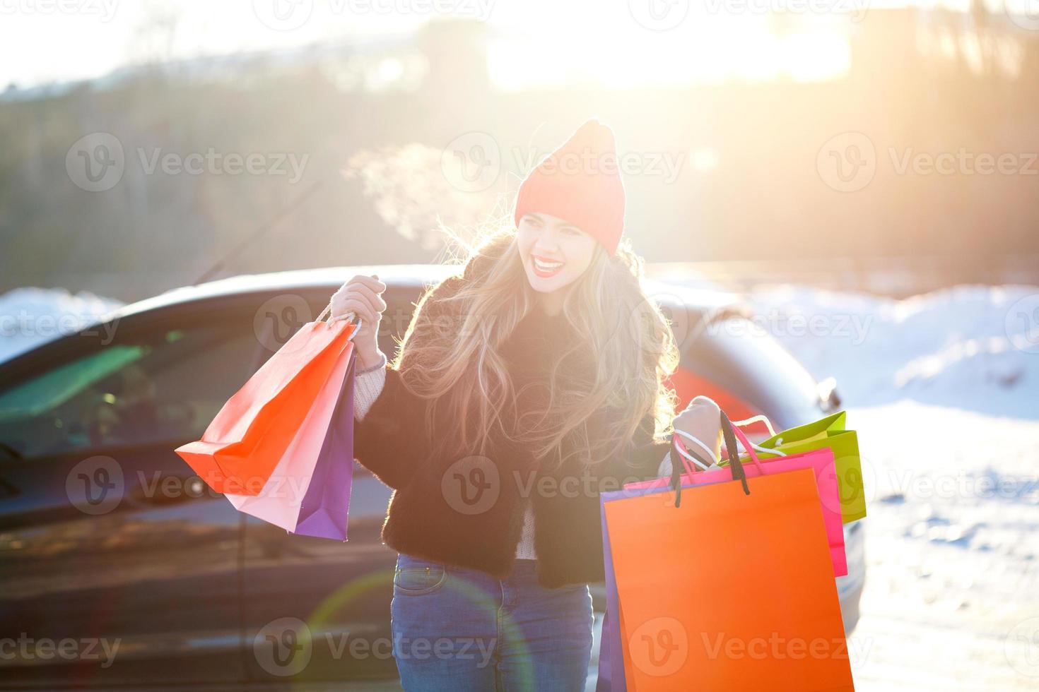 Smiling Caucasian woman holding her shopping bag near the car photo