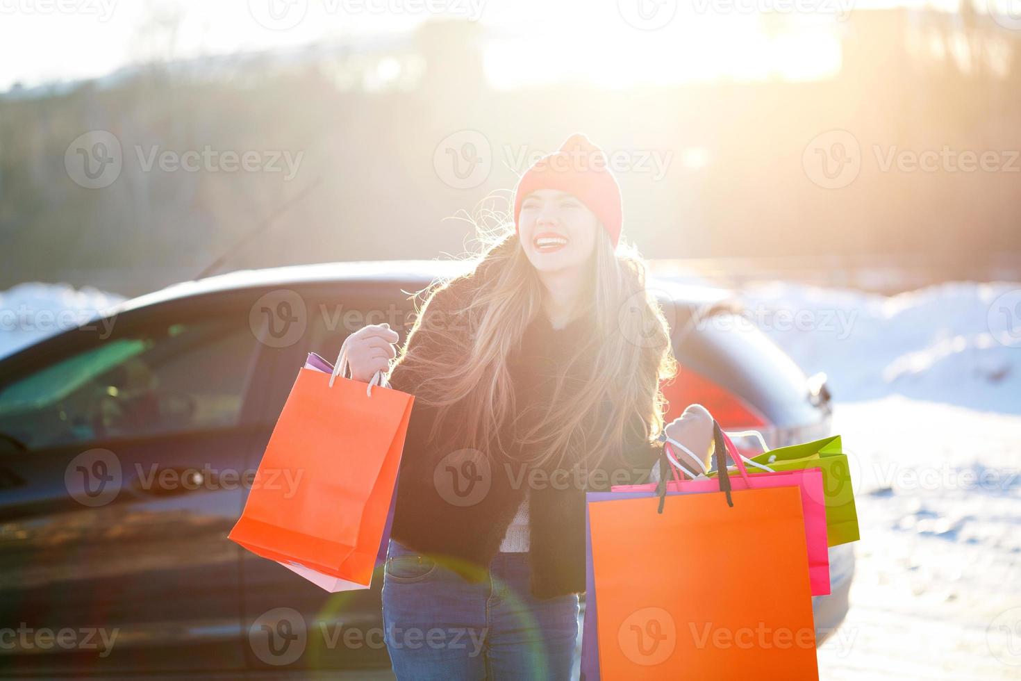 Smiling Caucasian woman holding her shopping bag near the car photo