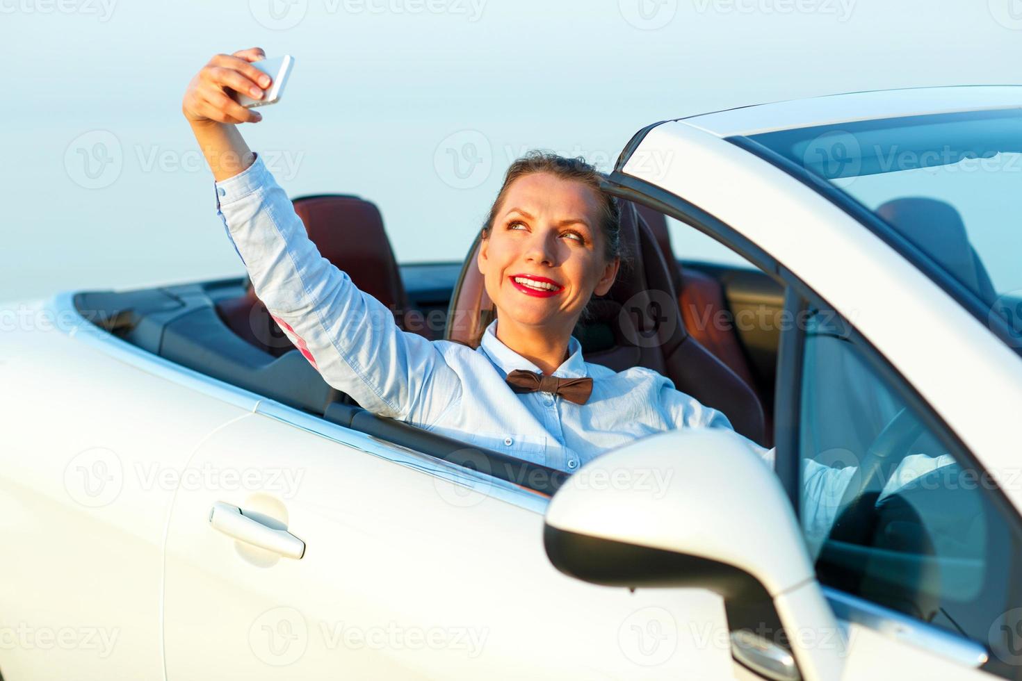 Young woman making self portrait sitting in the cabriolet photo