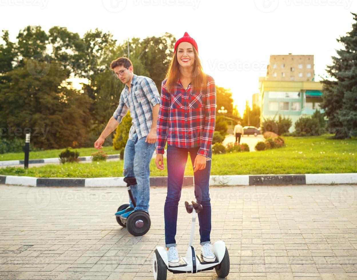 Young couple riding hoverboard - electrical scooter, personal eco transport, gyro scooter, smart balance wheel photo