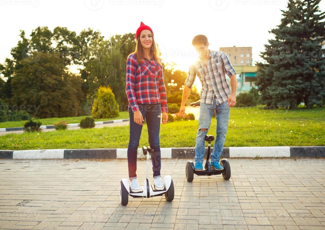 Young couple riding hoverboard - electrical scooter, personal eco transport, gyro scooter, smart balance wheel photo