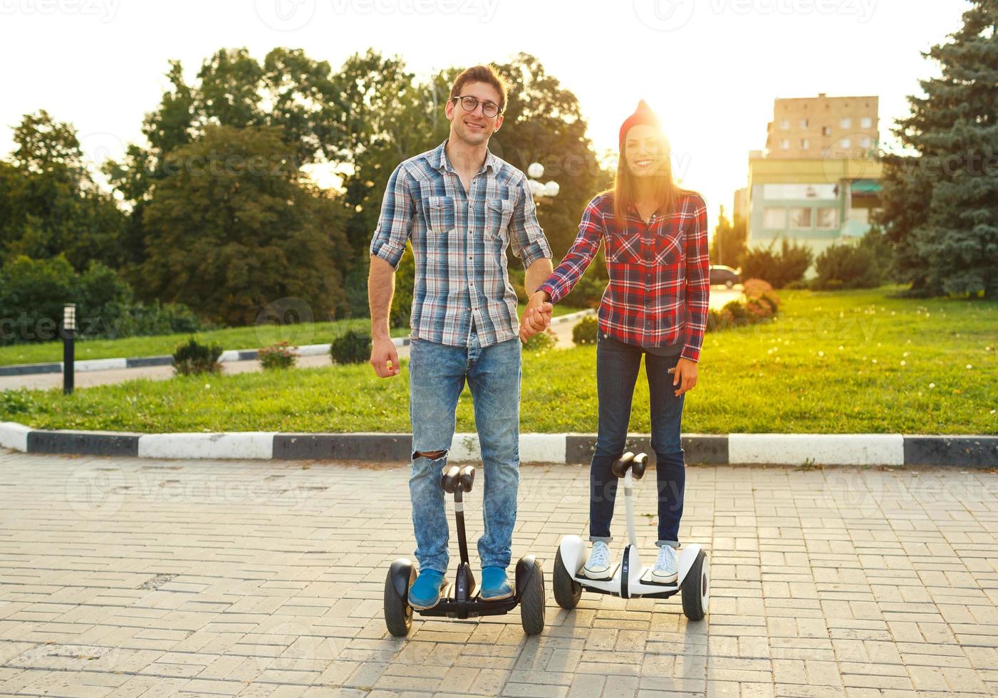 Young couple riding hoverboard - electrical scooter, personal eco transport, gyro scooter, smart balance wheel photo
