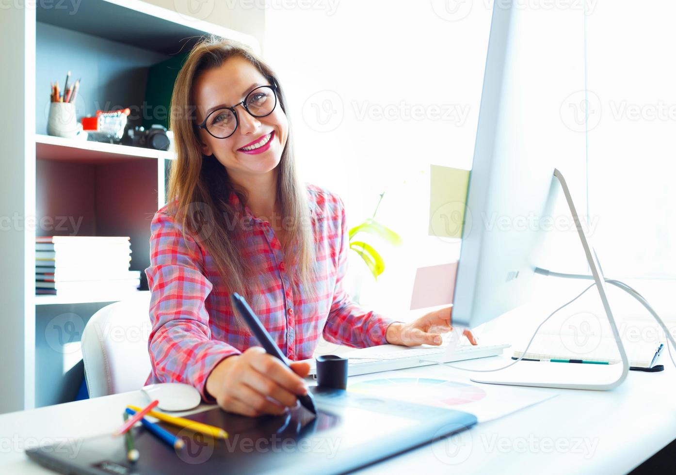 Woman drawing something on graphic tablet at the home office photo