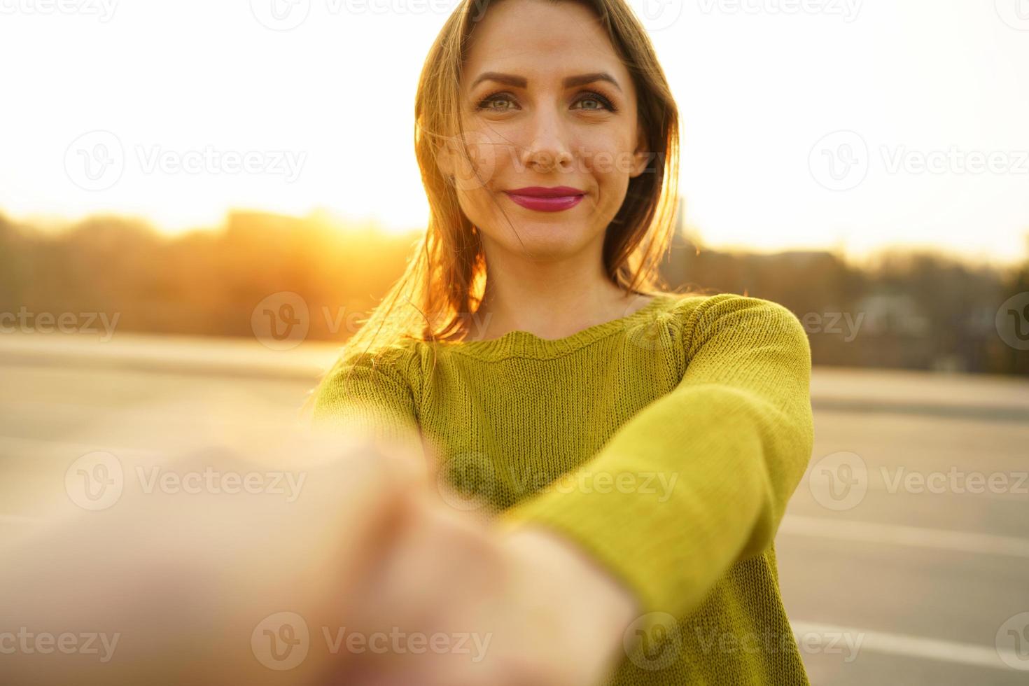 Happy young woman pulling guy's hand - hand in hand walking on a bright sunny day photo