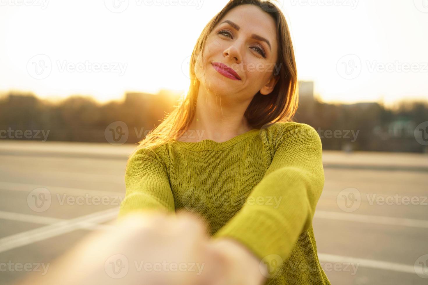 Happy young woman pulling guy's hand - hand in hand walking on a bright sunny day photo