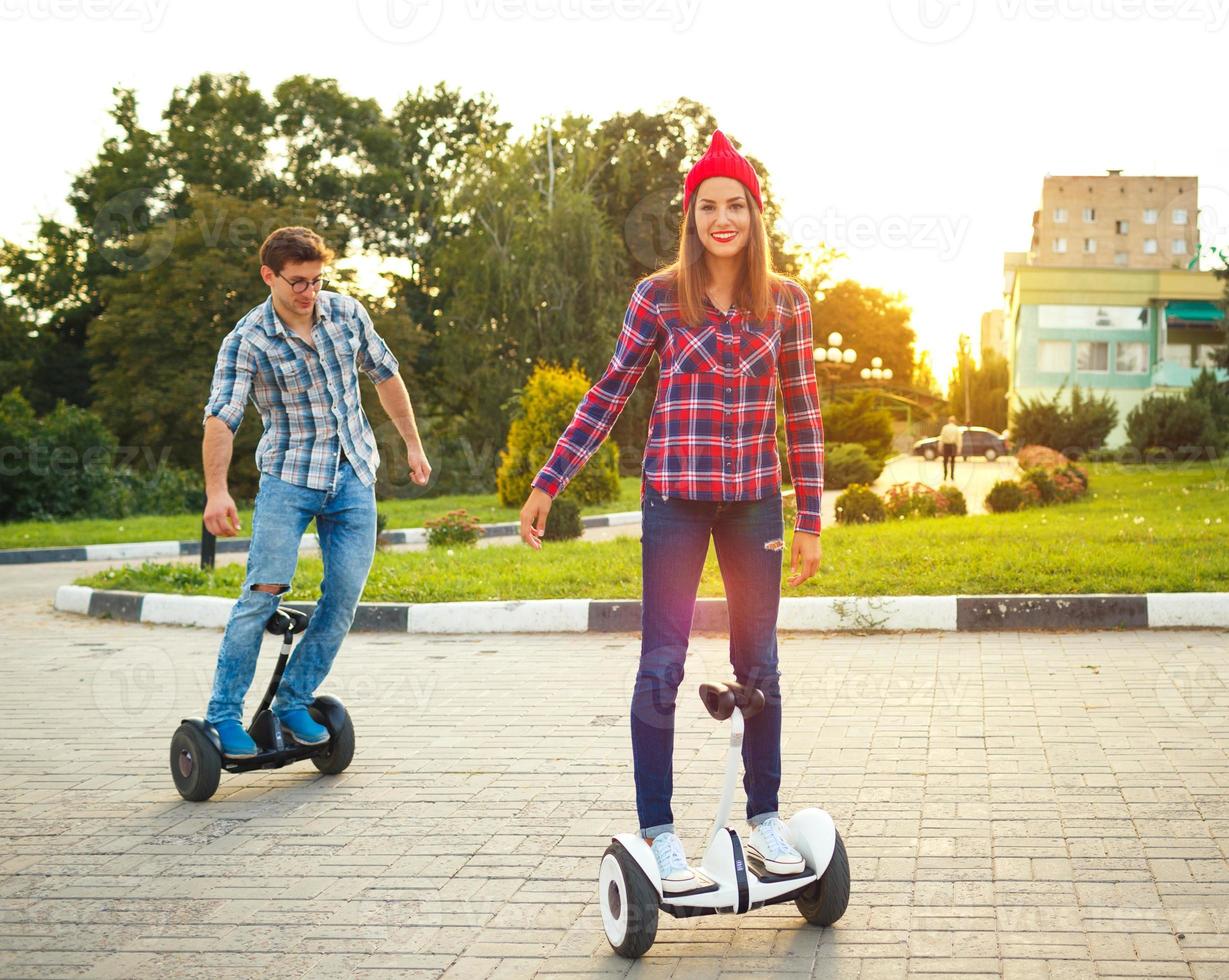 Young couple riding hoverboard - electrical scooter, personal eco transport, gyro scooter, smart balance wheel photo