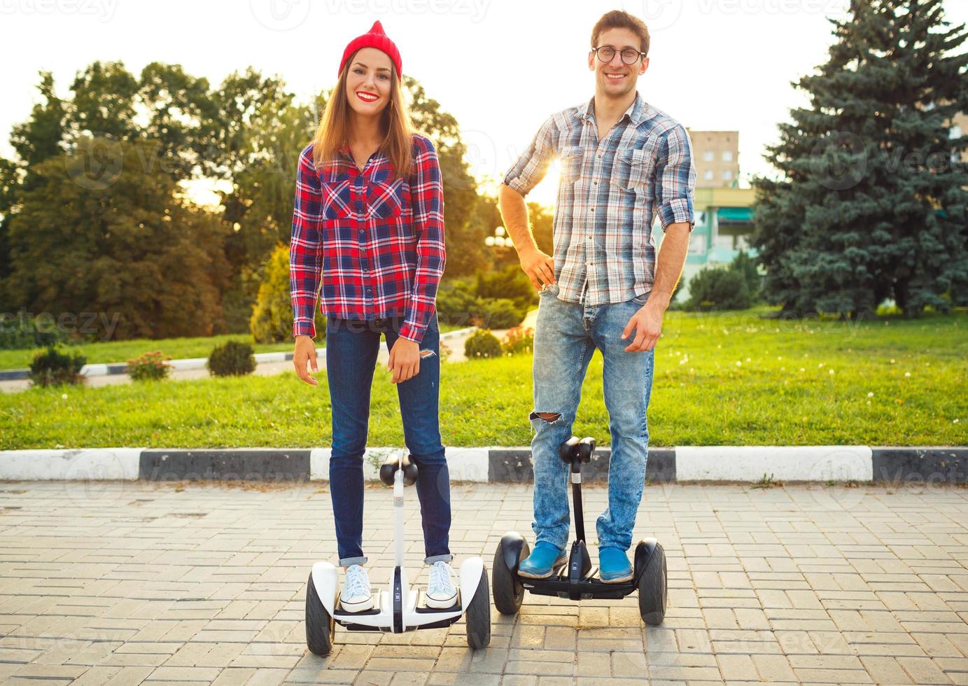 Young couple riding hoverboard - electrical scooter, personal eco transport, gyro scooter, smart balance wheel photo
