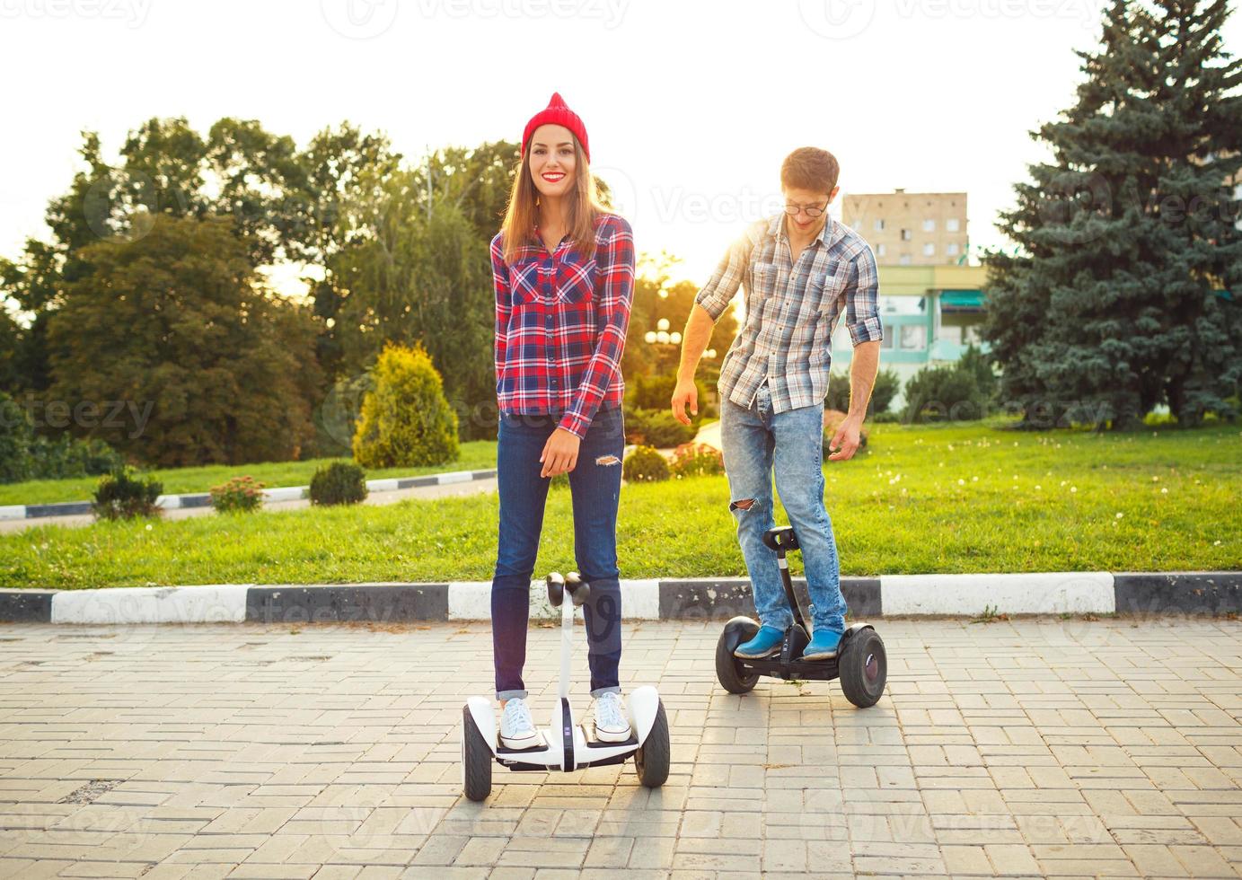 Young couple riding hoverboard - electric scooter, personal eco transport, gyro scooter, smart balance wheel photo