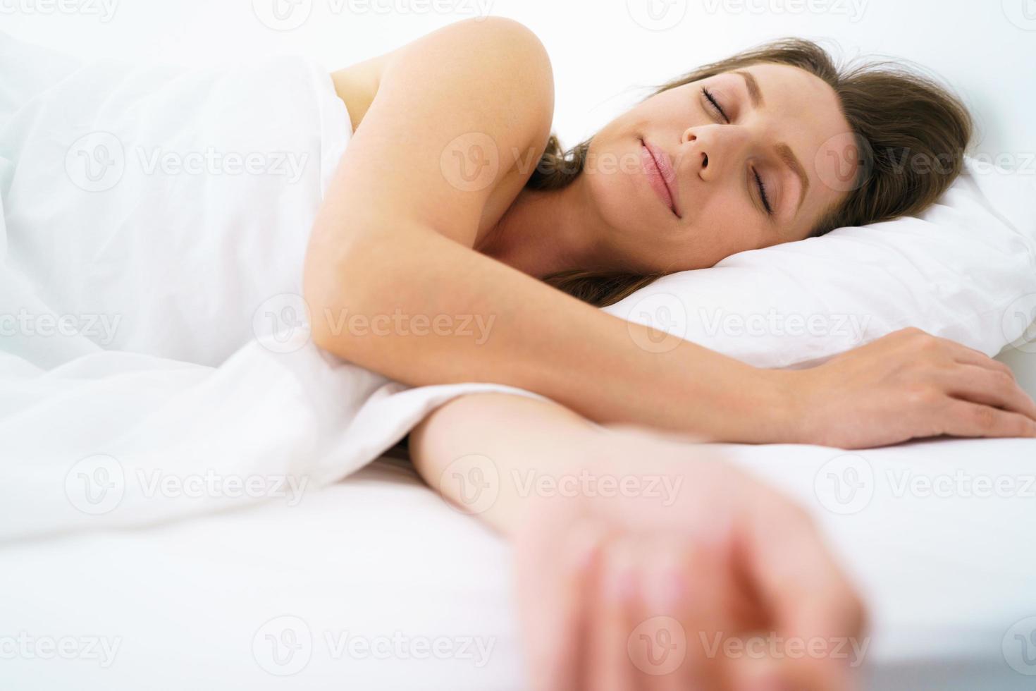 linda niña dormido en cama y sonriente a cámara foto