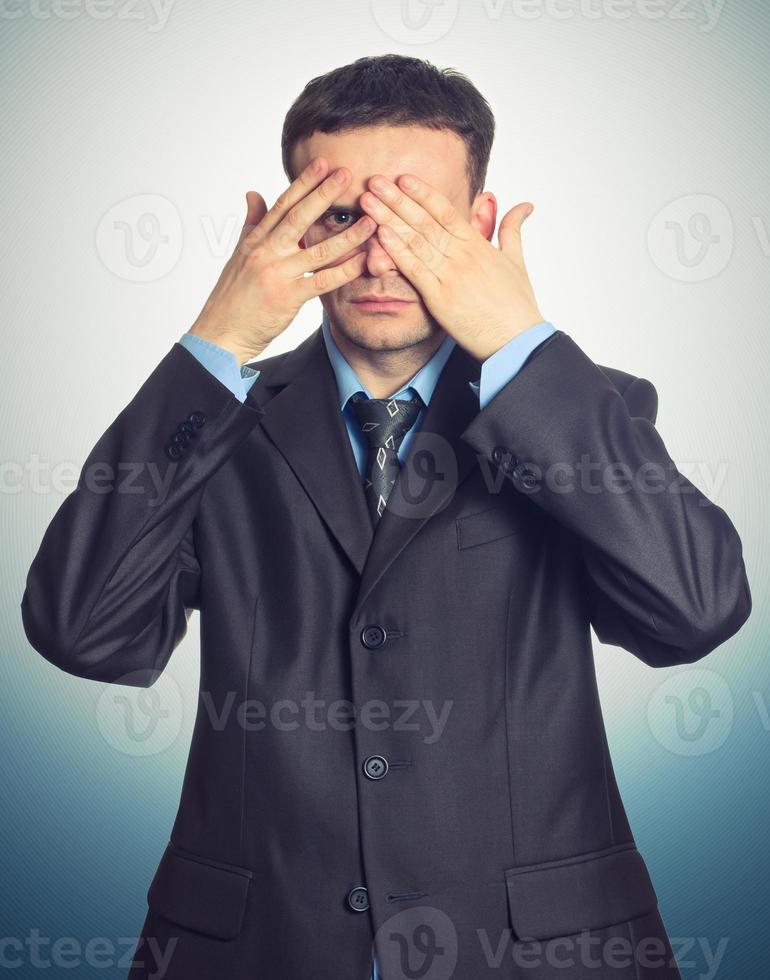 Young businessman looking through his fingers photo