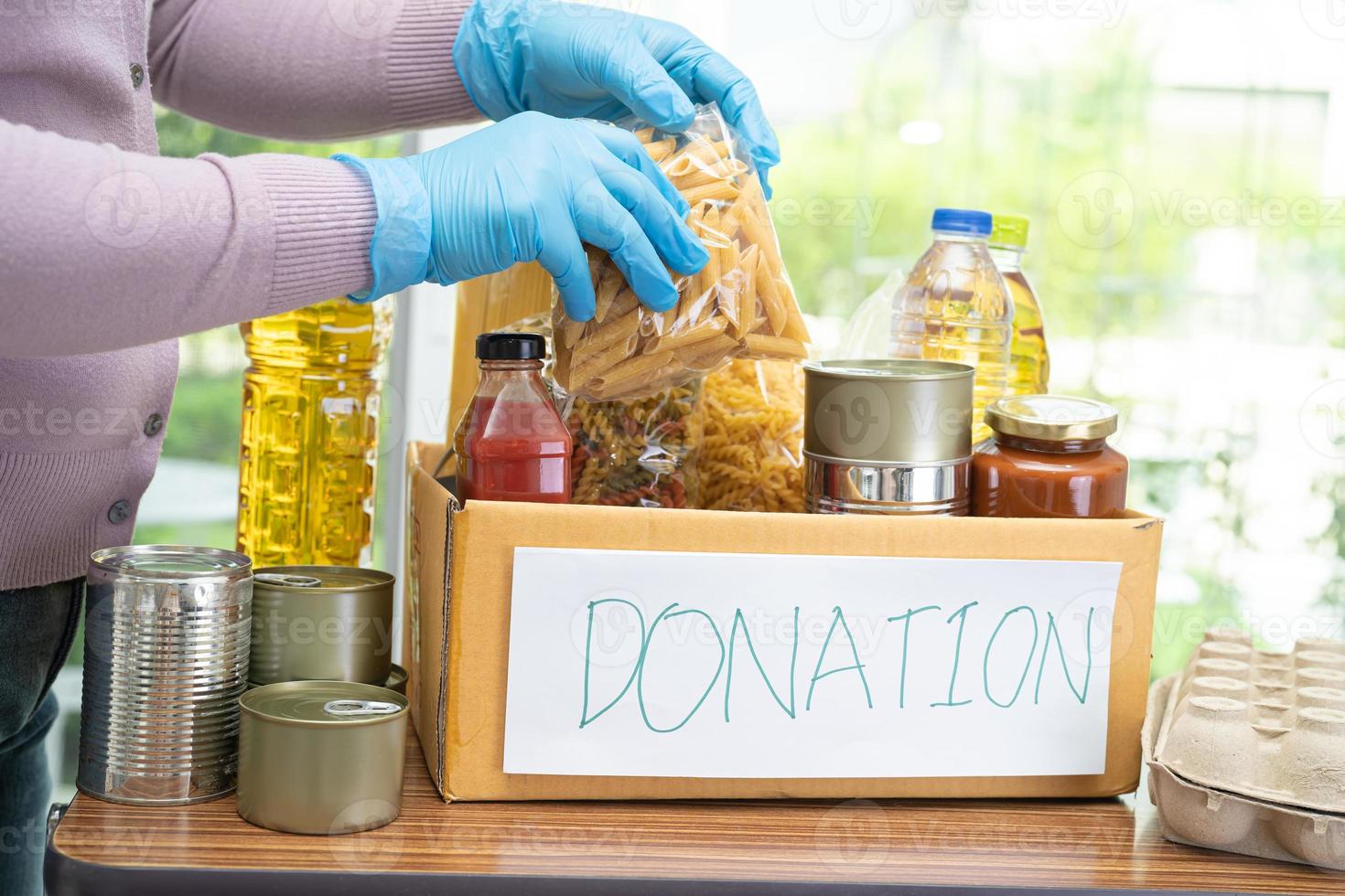 Volunteers putting various dry food in donation box for help people. photo