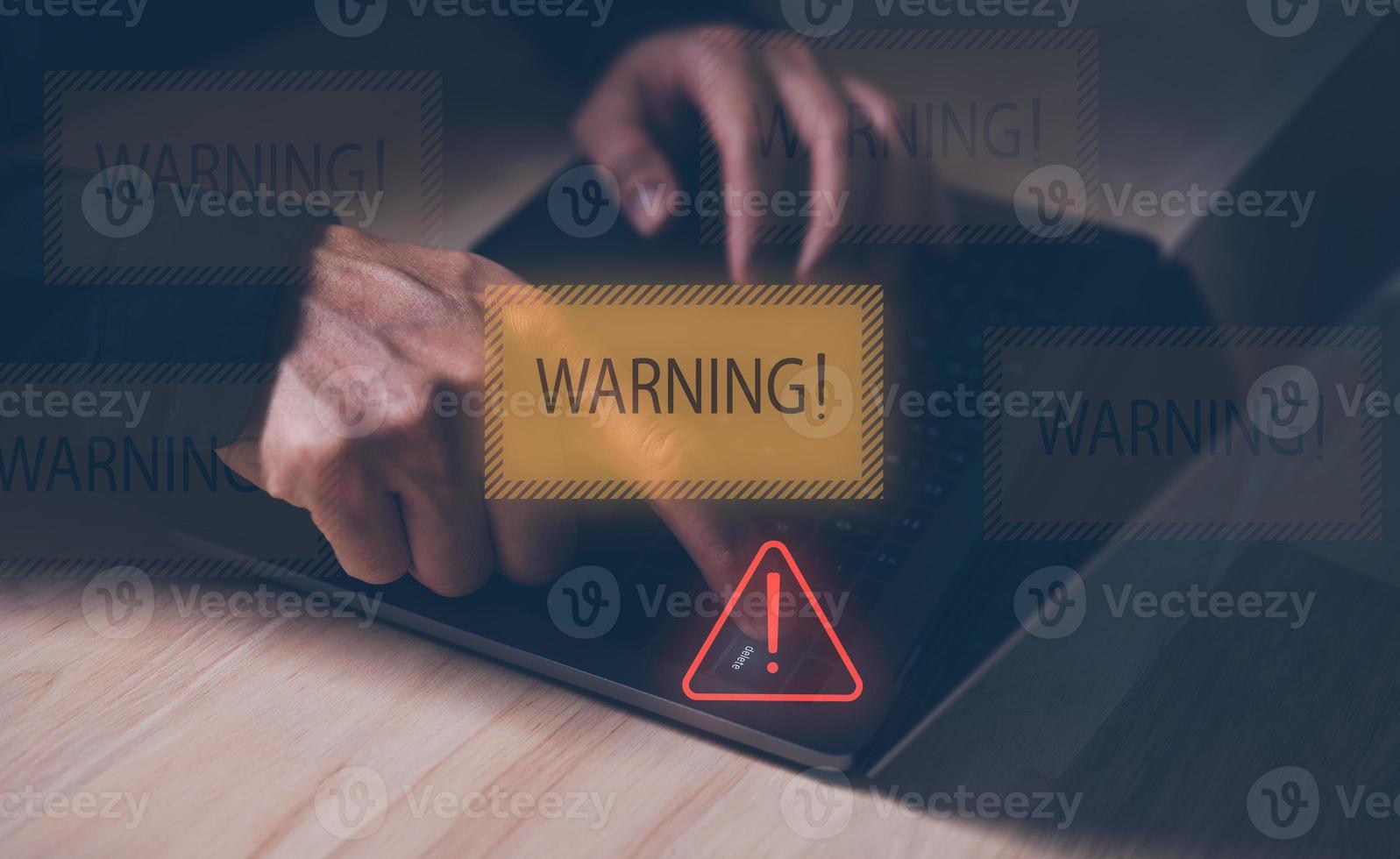 concept of security network media data safety, man pressing delete button on computer laptop with virtual warning and danger signs. protecting personal information. photo