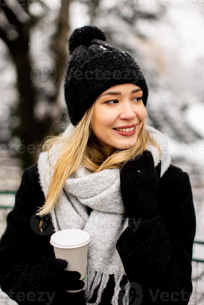 Young woman with Warm Clothes in Cold Winter Snow drinking coffee to go photo
