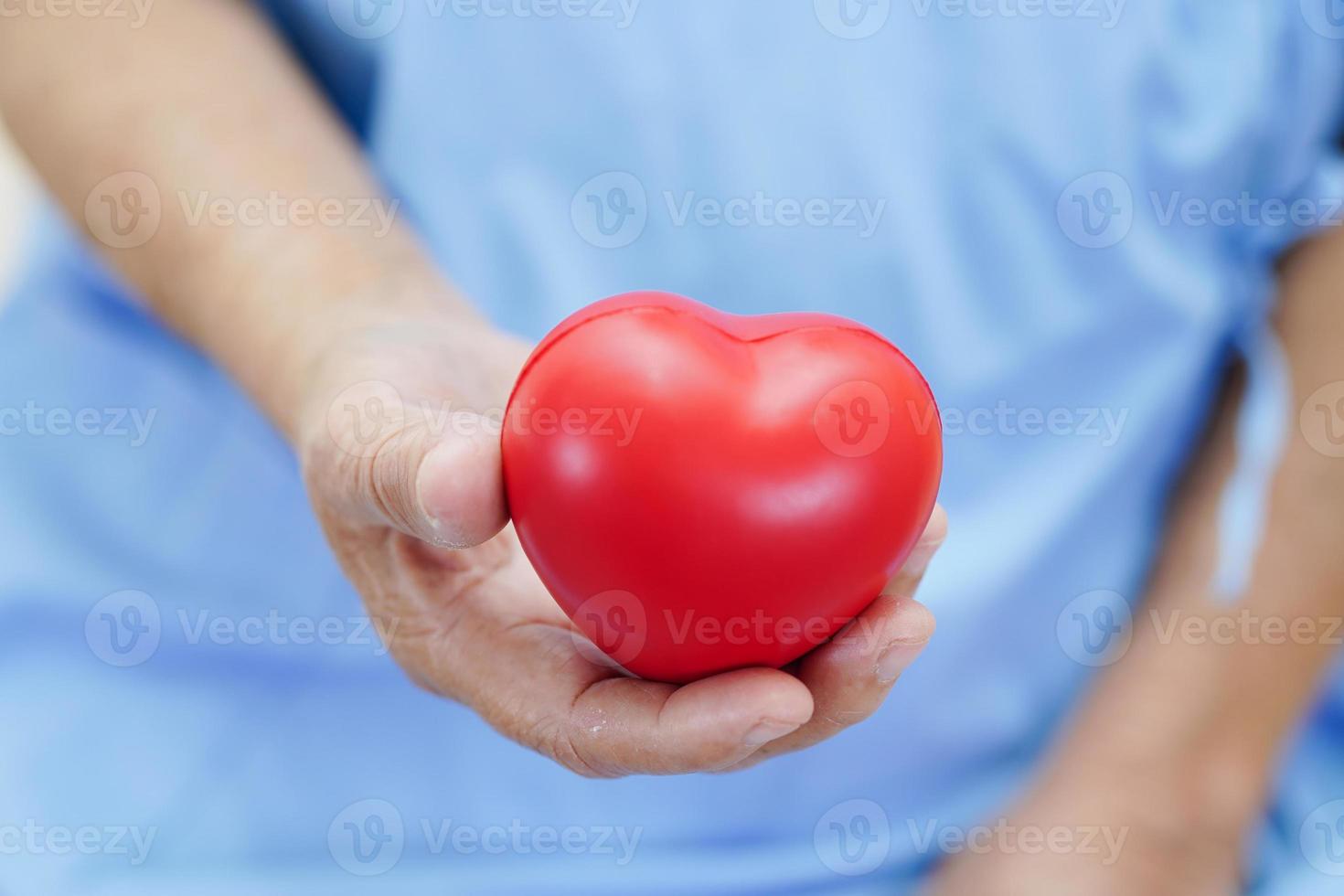 Asian elder senior woman patient holding red heart in hospital. photo