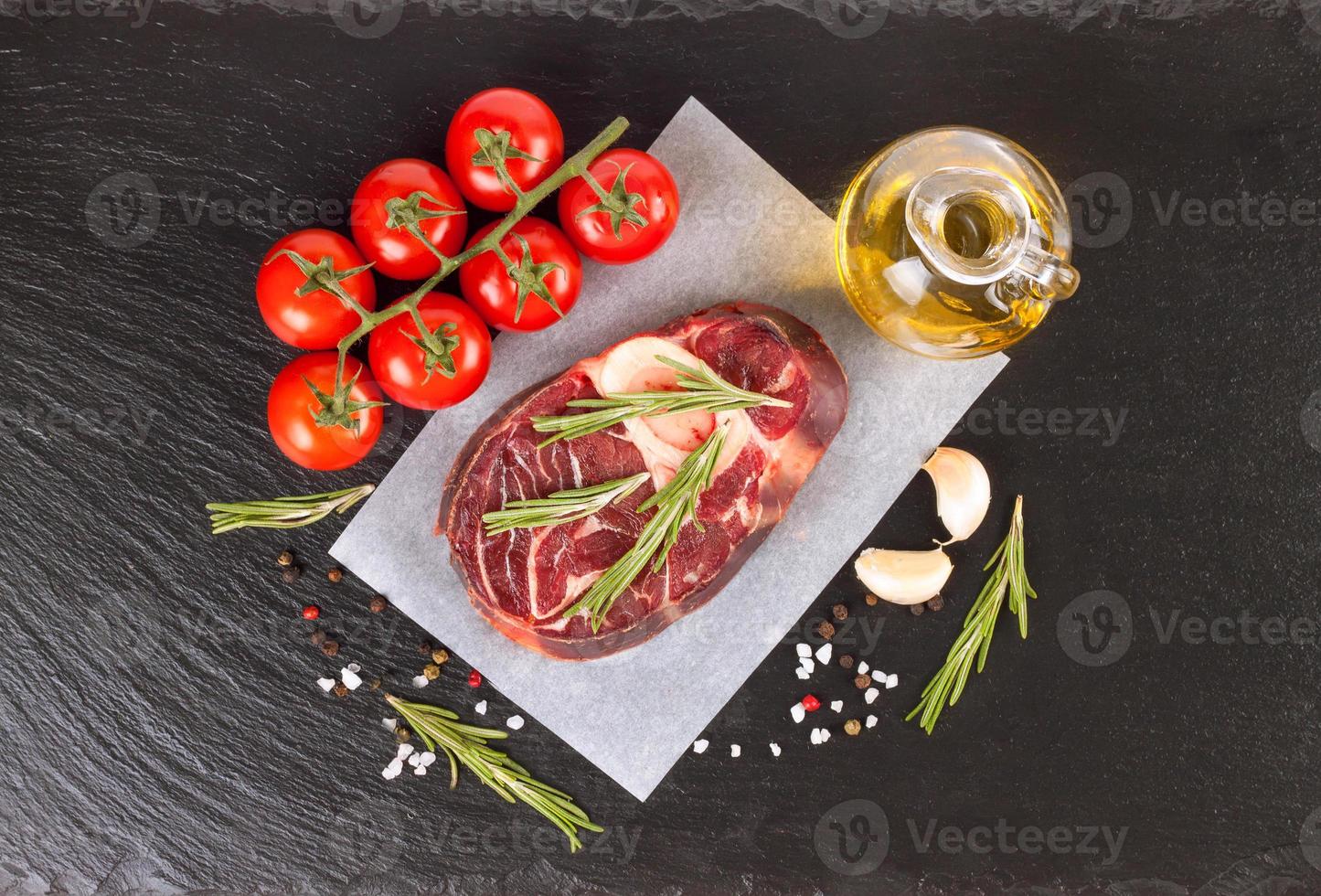 raw meat beef steak with bone on paper and black slate background. top view, flat lay. photo