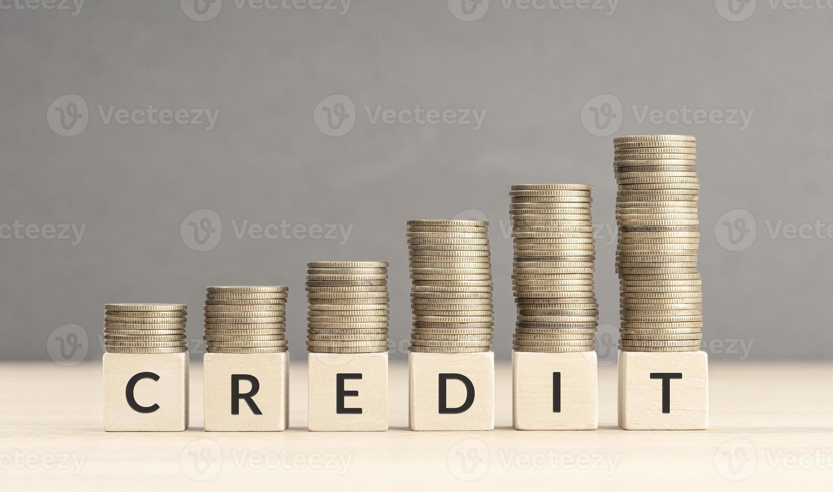 Credit increasing concept. Text word on wooden blocks with coins stacked in increasing stacks. Copy space photo