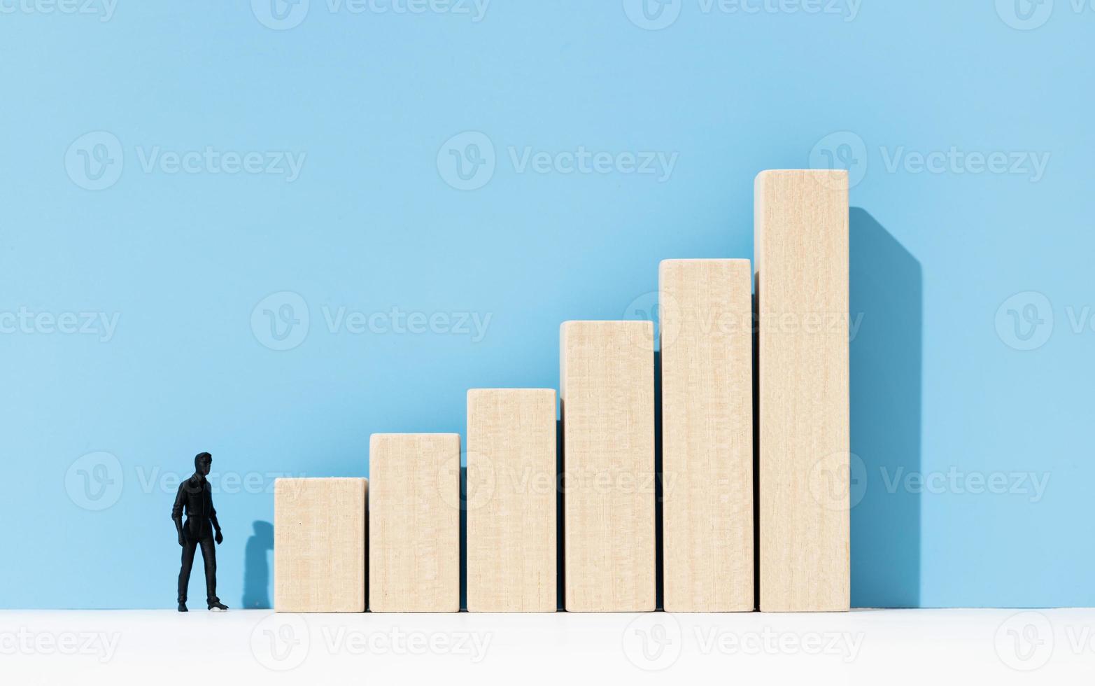 Human figurine looking at a growing bar chart. Career development concept. Copy space photo