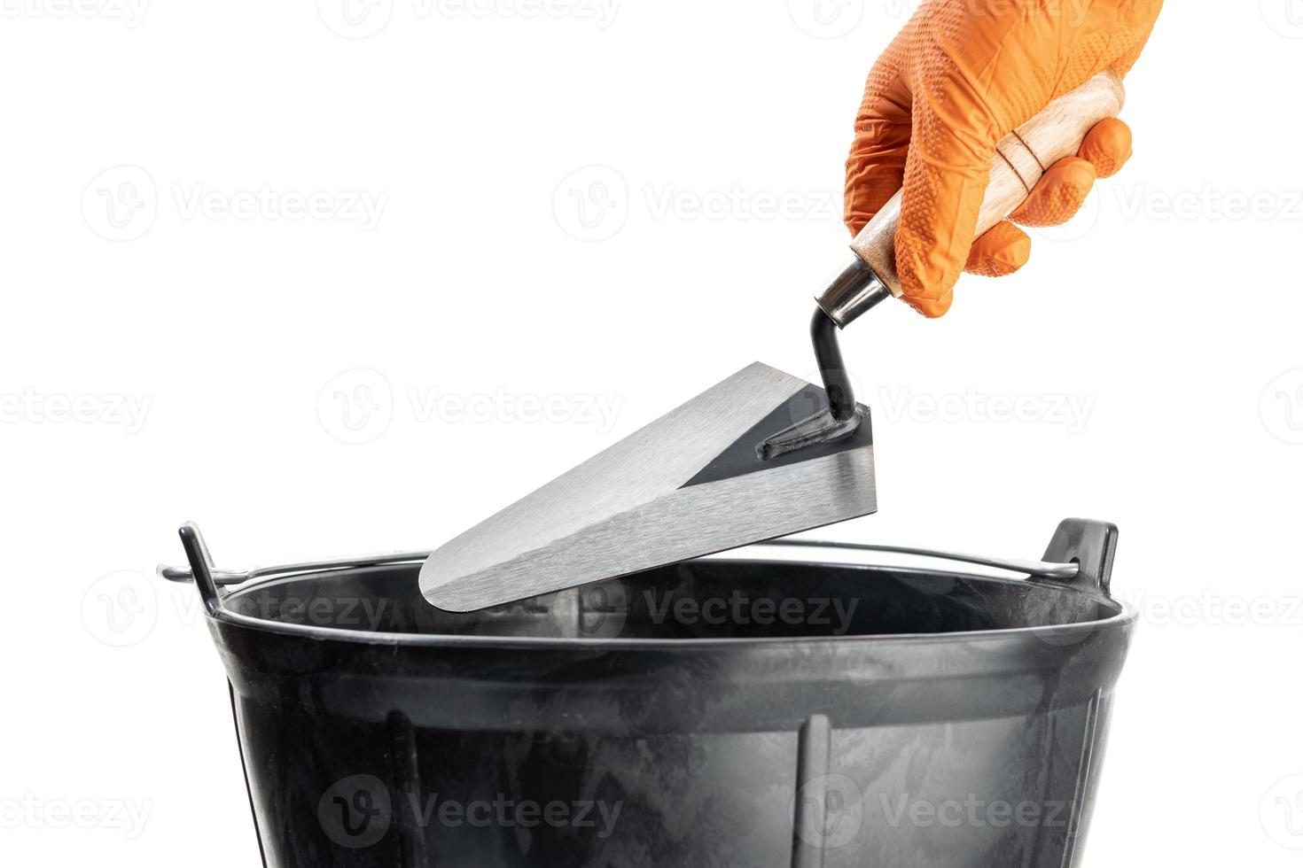 Hand Holding a Trowel over a mason bucket isolated on White Background. Copy space photo