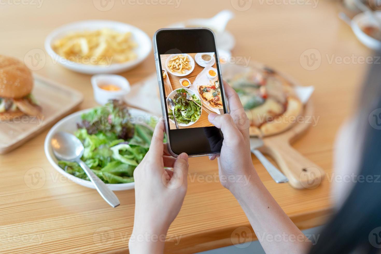 Woman take picture of a meal on the table after ordering food online to eat at home. Photography and use phone concepts photo