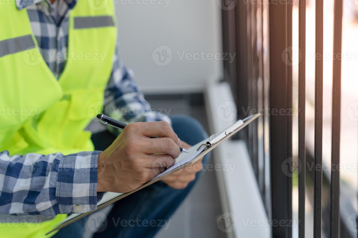 el inspector o ingeniero está inspeccionando la construcción y el aseguramiento de la calidad de la nueva casa usando una lista de verificación. ingenieros o arquitectos o contratistas trabajan para construir la casa antes de entregársela al propietario foto