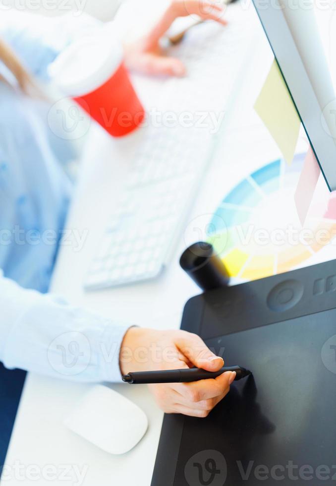 Woman drawing something on graphic tablet at the home office photo