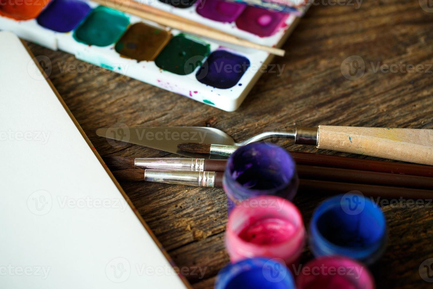 Paper, watercolors and paint brush on wooden background photo