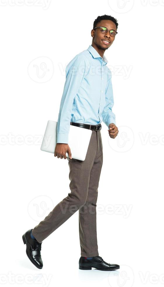 Happy african american college student with laptop standing on white photo