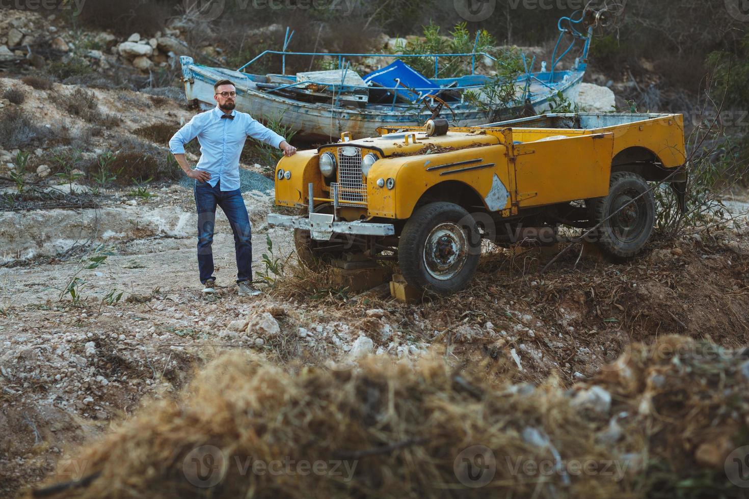 Young stylish man with glasses and bow tie near the old-fashioned SUV photo