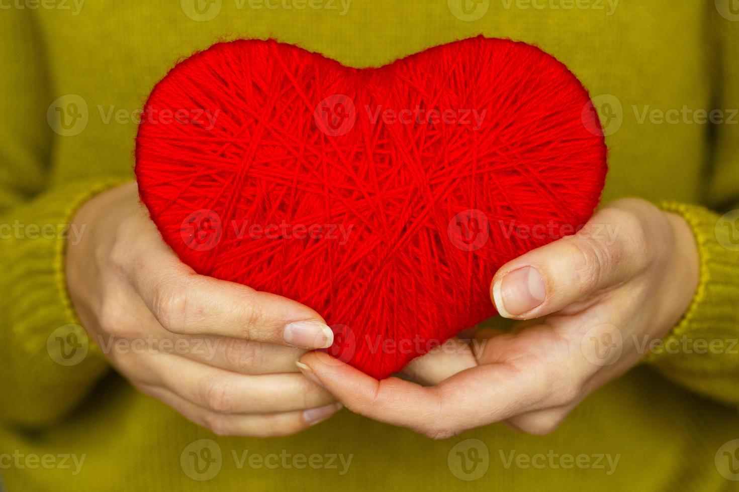 Closeup on red heart made from wool in hand of woman photo