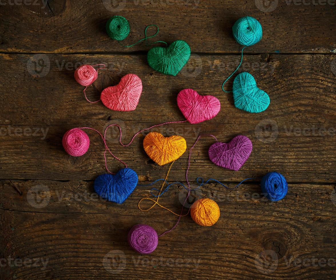 Multicolored Hearts with a balls of thread on old shabby wooden background photo