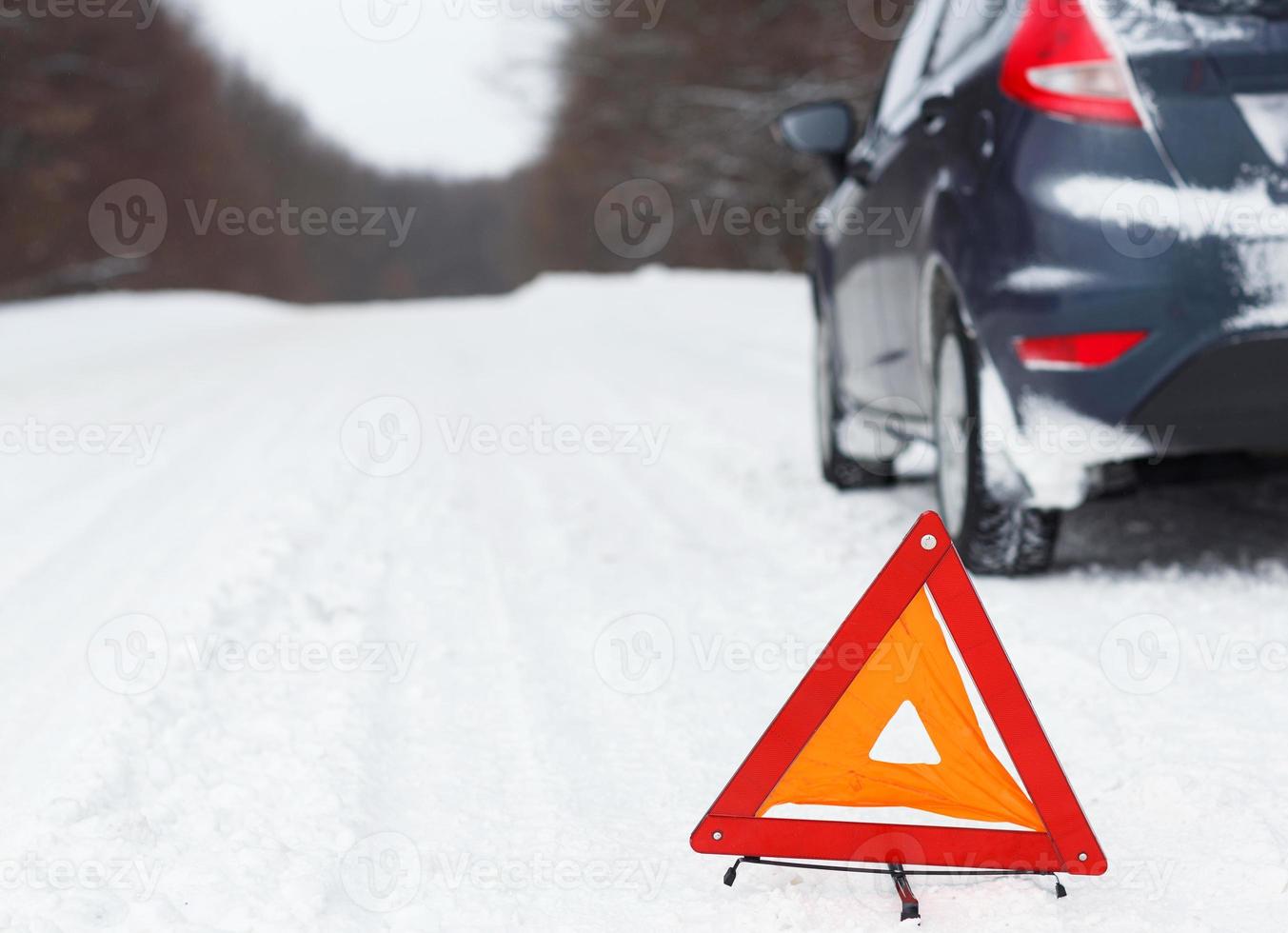 Closeup of red warning triangle with a broken down car photo