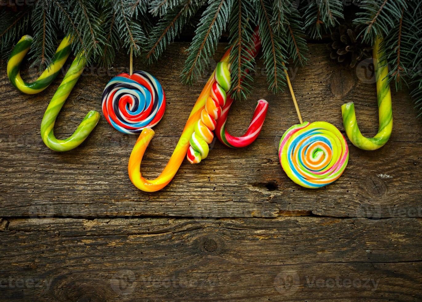 Christmas border with fir tree branches, pine cones and candy cane on rustic wooden boards photo