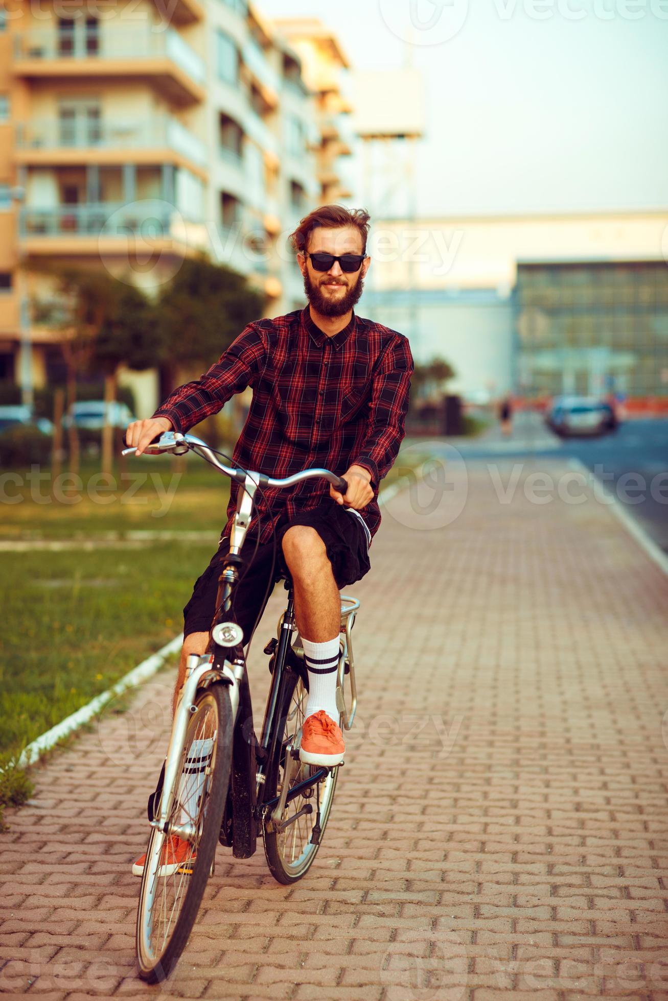 joven hombre en Gafas de sol montando un bicicleta en ciudad calle