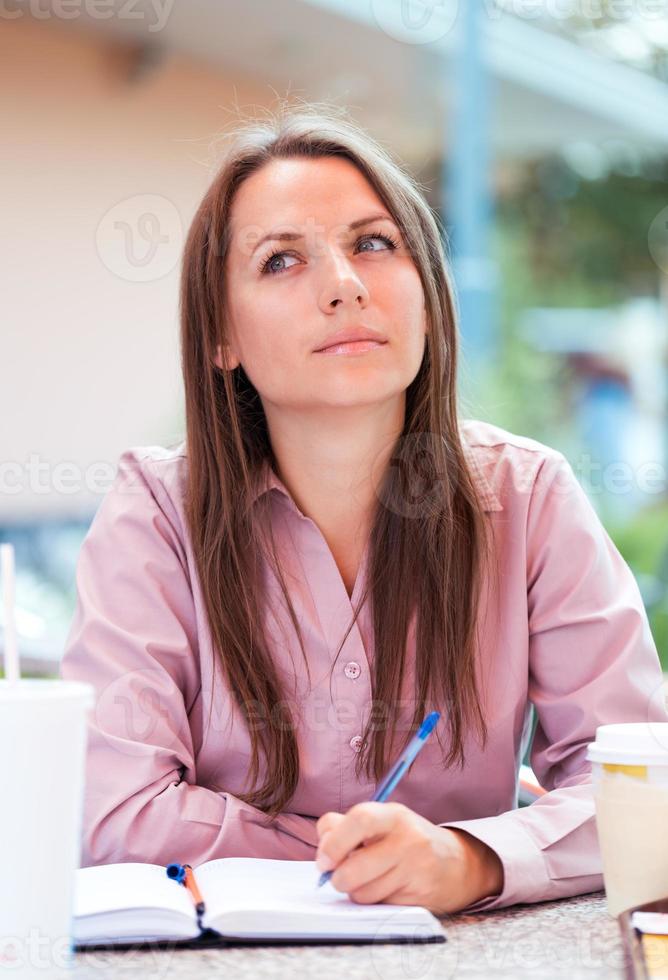 Businesswoman sitting in a cafe and writing in notepad or organizer photo