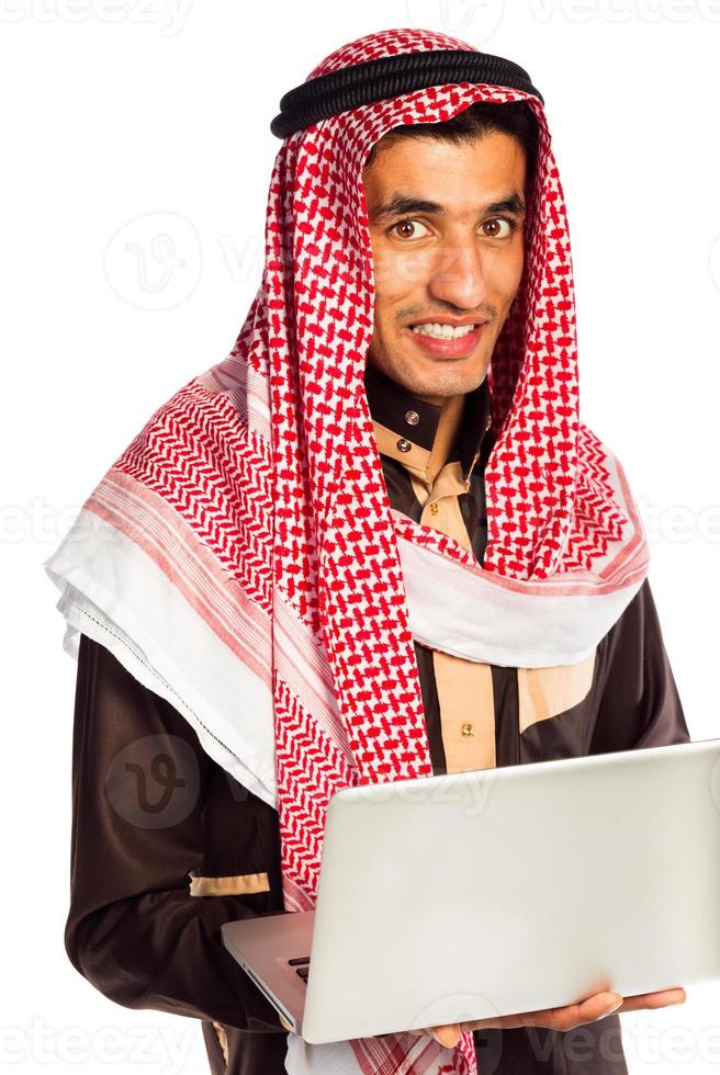 joven sonriente árabe con ordenador portátil aislado en blanco foto