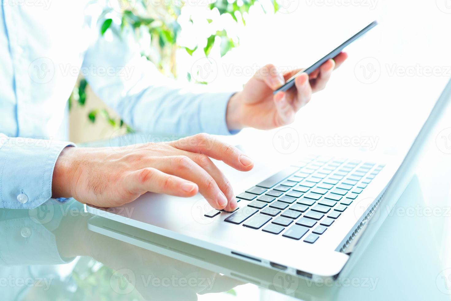 Men office worker typing on the keyboard and using smartphone photo