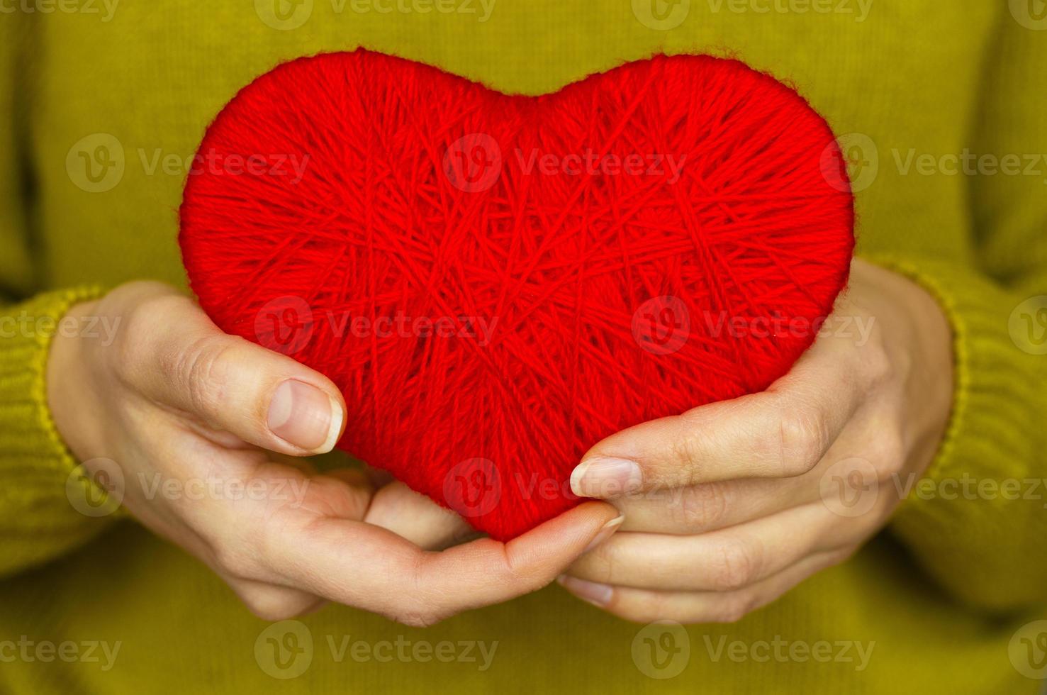 Closeup on red heart made from wool in hand of woman photo