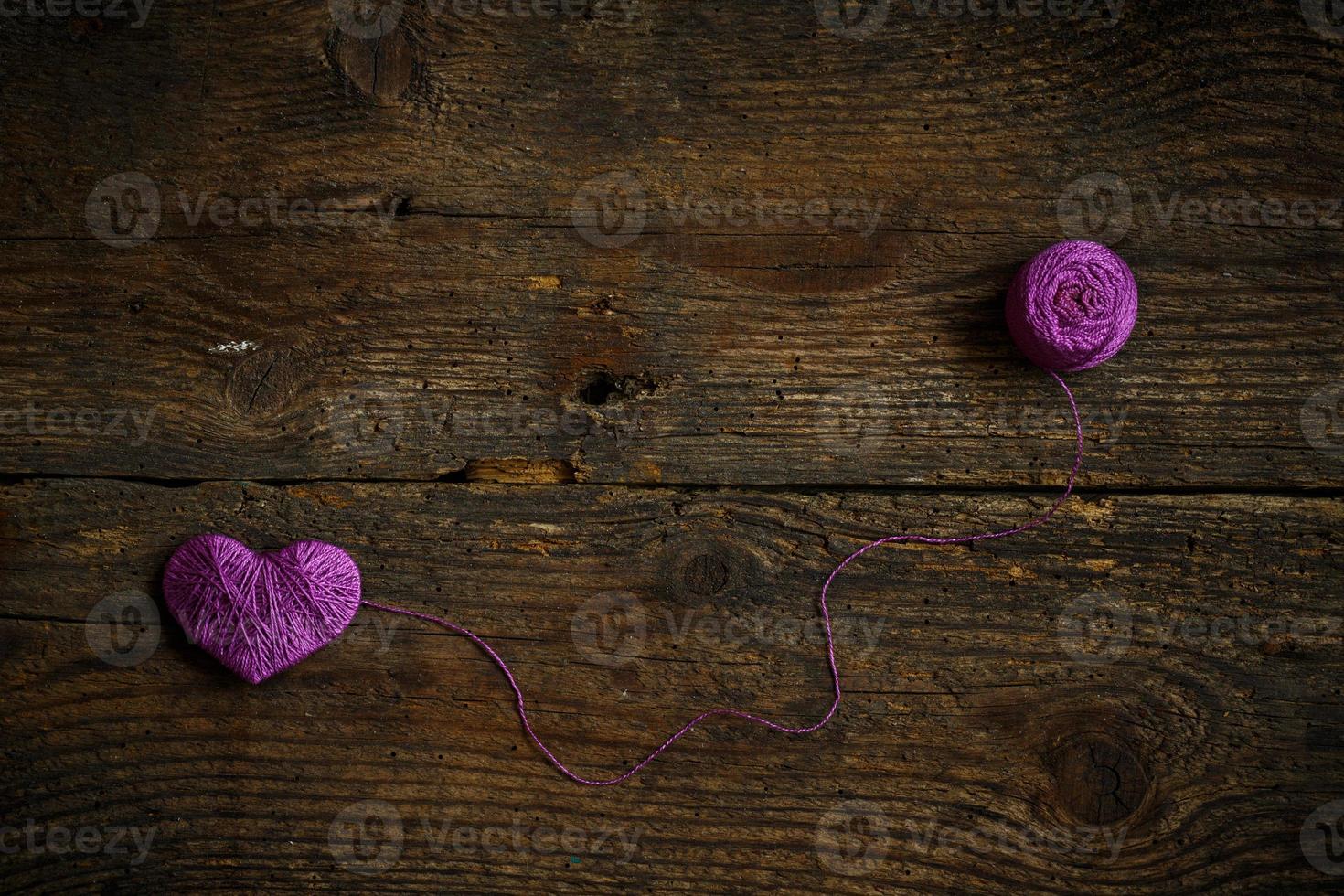 Purple Heart with a ball of thread on on old shabby wooden background photo