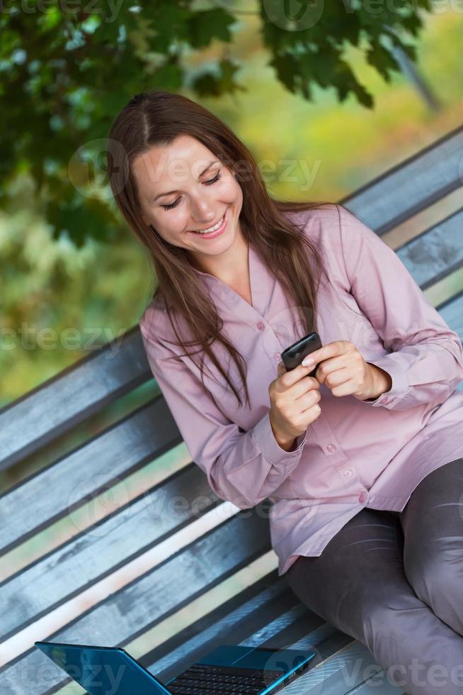 Businesswoman with cellphone and laptop photo