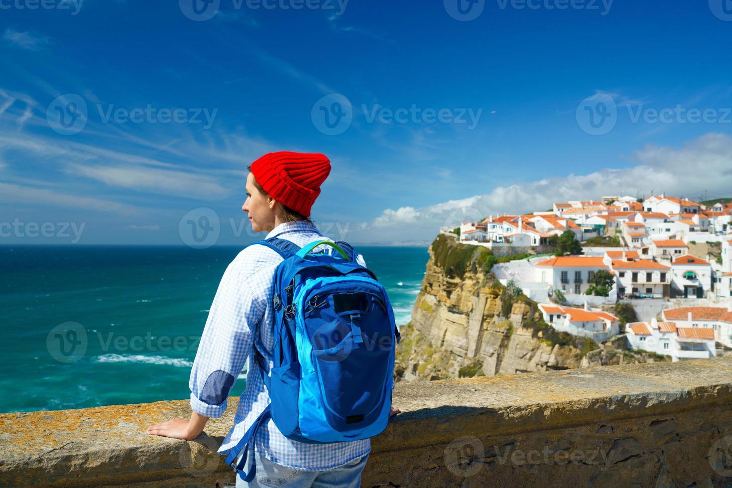 Woman with a backpack enjoys a view of the ocean coast near Azenhas do Mar, Portugal photo